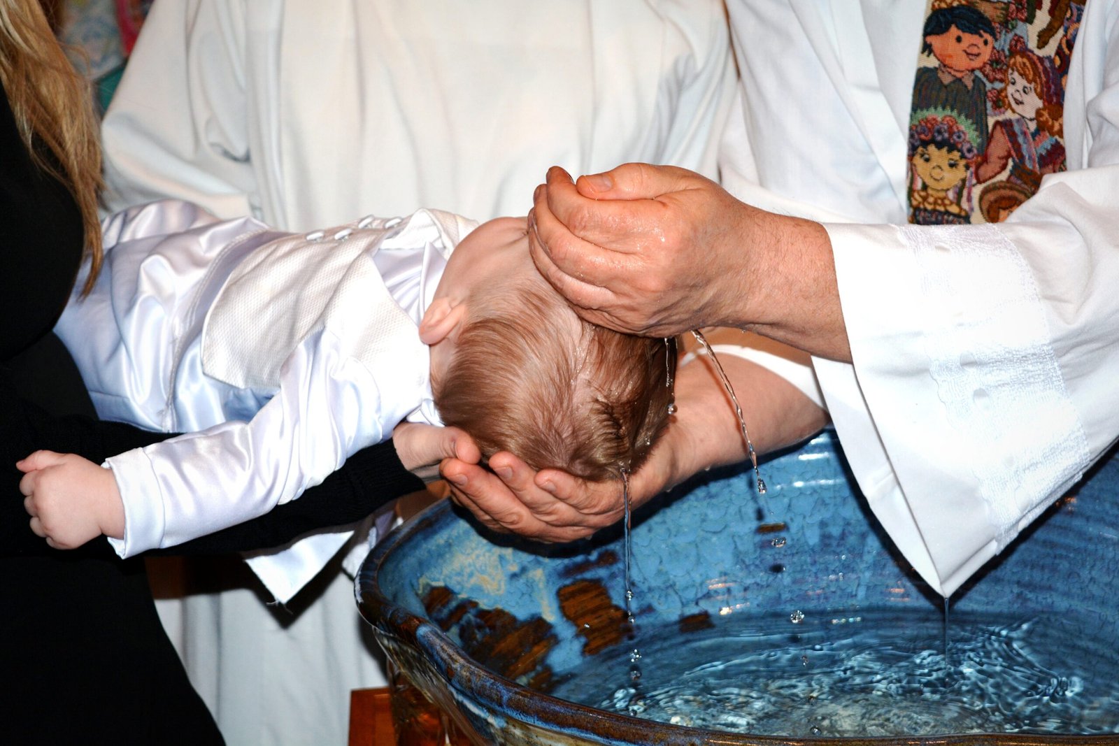 midsection-priest-pouring-water-baby-boy-head